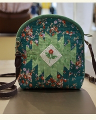 A fabric shell crossbody bag with handmade embroidery and a zipper